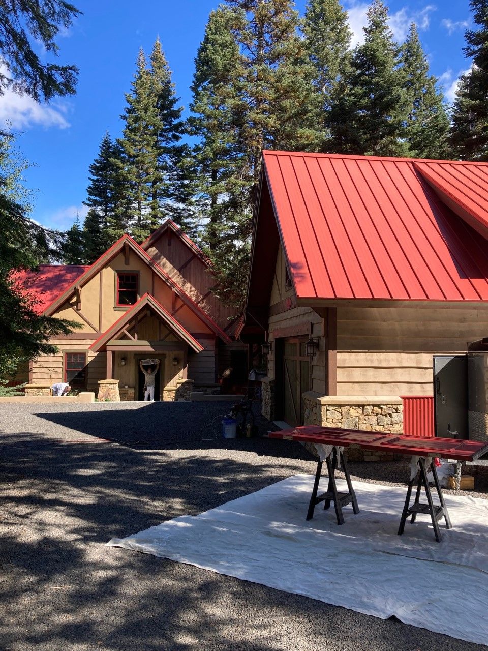 Log cabin with a red metal roof and a door drying on sawhorses