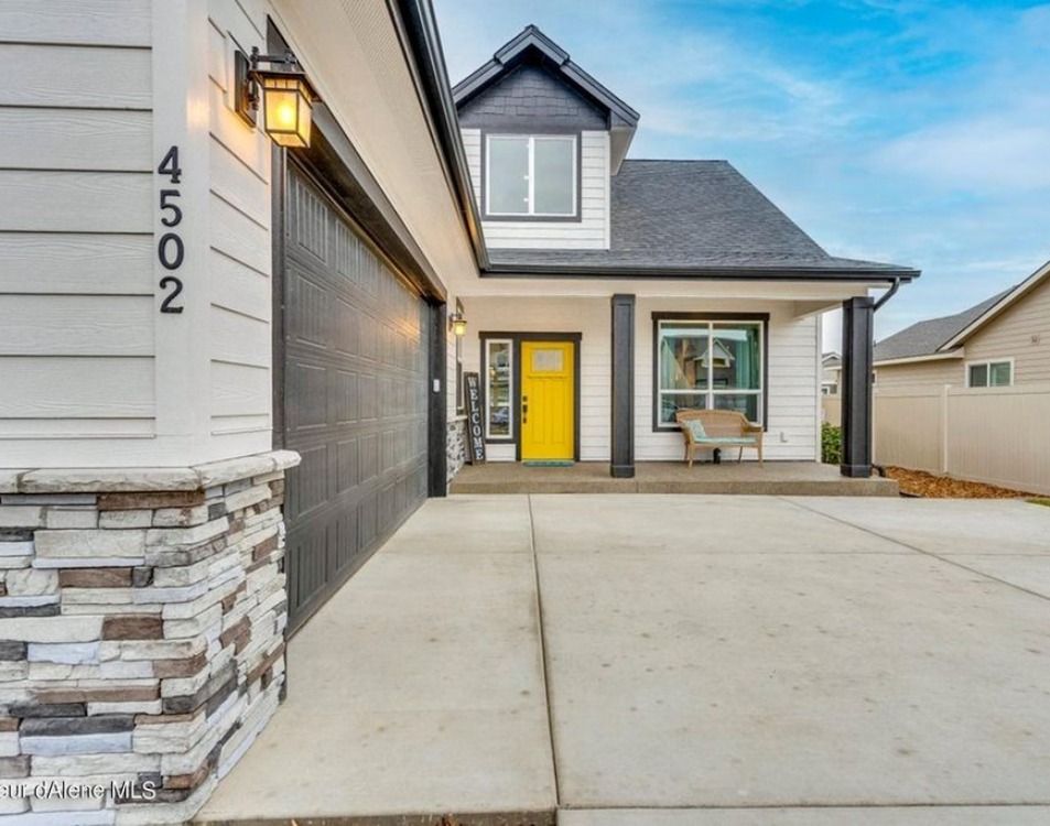 New home with dark grey siding, stone base and a yellow front door