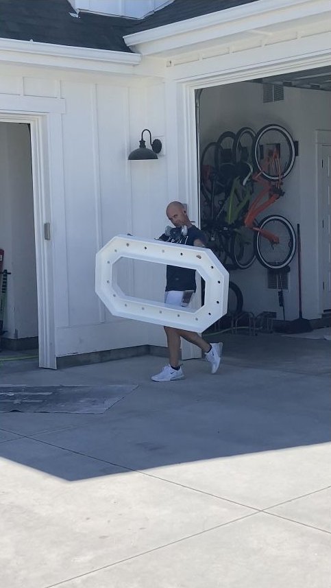 Paul carrying a freshly painted white door through a garage